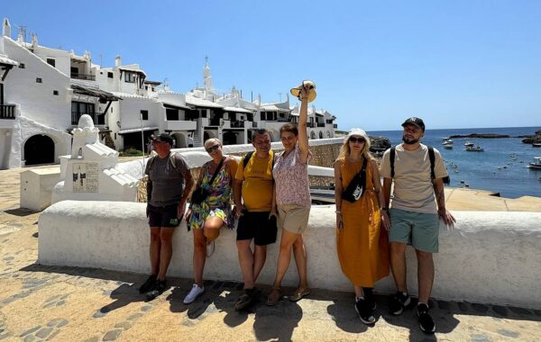 Grupa turystów zwiedzająca Binibeca Vell na Minorce – białe domy, widok na morze i malownicza atmosfera tradycyjnej wioski rybackiej.