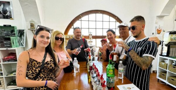 Grupa turystów uczestniczy w degustacji lokalnych trunków na Minorce, próbując tradycyjnych likierów i ginu.