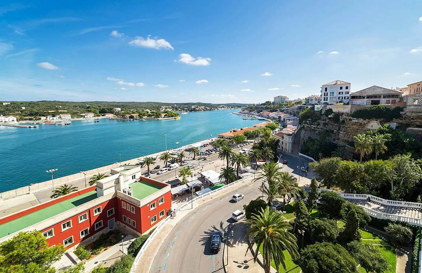 Widok na port Mahón na Minorce – najdłuższy naturalny port na Morzu Śródziemnym, otoczony malowniczą zabudową i palmami.